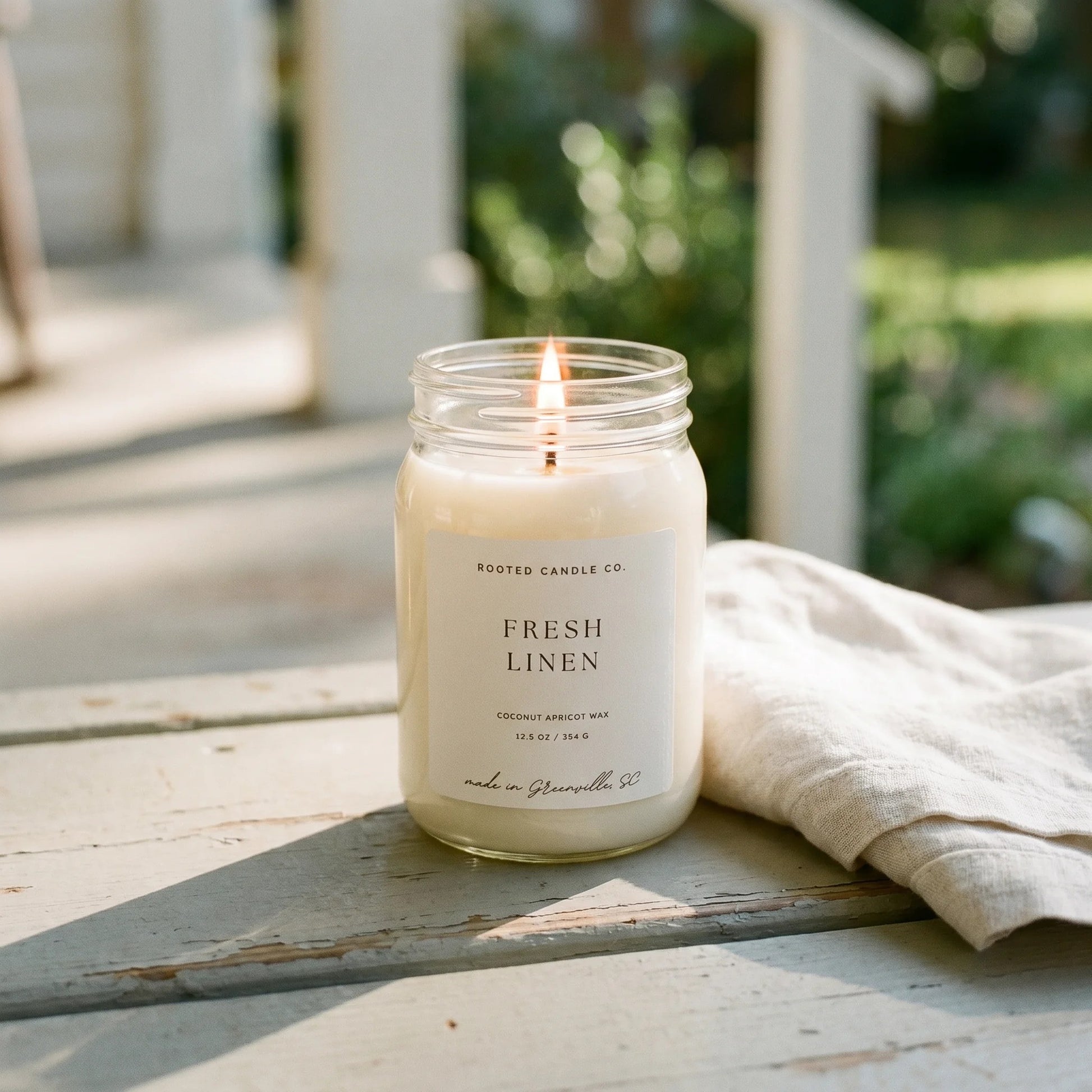 Fresh Linen candle on weathered porch step with folded linen napkin